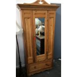 A small pine hanging wardrobe with mirror door and swan neck pediment, above single drawer,