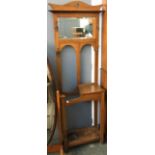 An oak coat and stick stand, having bevelled glass mirror and coat hooks, hinged lidded