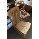 A caned bedroom chair, together with one other and an embroidered cushion