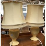 A pair of pale yellow ceramic baluster form table lamps, with shades, each 44cmH to top of shade
