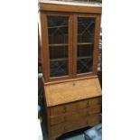 An early 20th century oak bookcase bureau with chequered stringing, lead glazed doors above fall