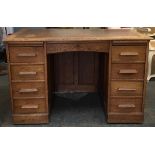 A 20th century oak kneehole desk, tooled leather skiver above the traditional arrangement of nine