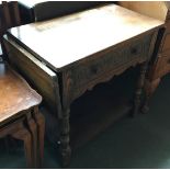 An early 20th century oak side table, drop flaps to either end, single carved frieze drawer, on