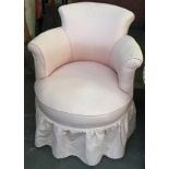 A small circular bedroom chair, upholstered in a pink fabric