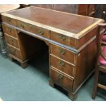 A kneehole desk, cloth inset top over the traditional arrangement of nine drawers, 123x59x77cmH