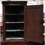 An oak corner cupboard, ormolu mounts over cupboard door opening to three shelves, canted corners,