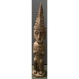 An African tribal carving of a seated man with headdress, 95cmH
