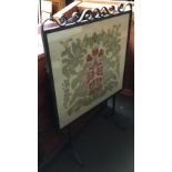 A wrought iron glazed embroidered fire screen, 77x122cm