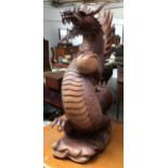 A large Oriental hardwood carving of a dragon (some damage), clutching an orb, 67cmH