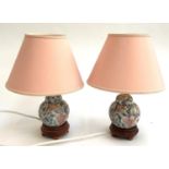 A pair of modern Oriental table lamps with pink shades, on hardwood turned bases