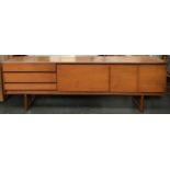 A very long teak mid century sideboard, comprising three drawers, fall front cupboard, and sliding