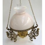 A hanging brass oil lamp with pierced spandrels, light pink milk glass shade and glass chimney