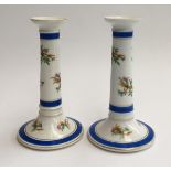 A pair of ceramic candlestick holders, decorated with floral sprays, heightened in gilt, marked '