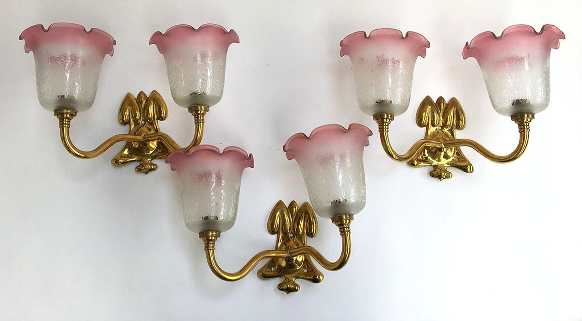 A set of three two-light fitting gilt metal sconces, with pink milk glass shades