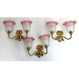 A set of three two-light fitting gilt metal sconces, with pink milk glass shades