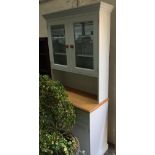 A modern painted kitchen dresser, glazed cupboard doors over beechwood top, above base with two