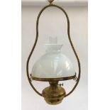A hanging brass oil lamp with rope twist detail, milk glass shade and glass chimney