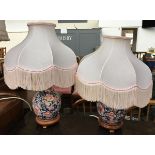 A pair of oriental ceramic table lamps, on carved bases, with tasseled shades