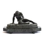 A 19th century carved serpentine statue 'The Dying Gaul', raised on a stepped oval plinth, which