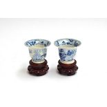 A pair of 19th century Chinese blue and white tea cups, marked to base, on hardwood plinths, 5.5cm