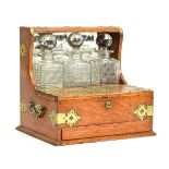 A three decanter oak tantalus with brass fittings, single drawer below