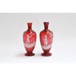 A pair of Mary Gregory style cranberry glass baluster vases (af), hand painted with white enamel,