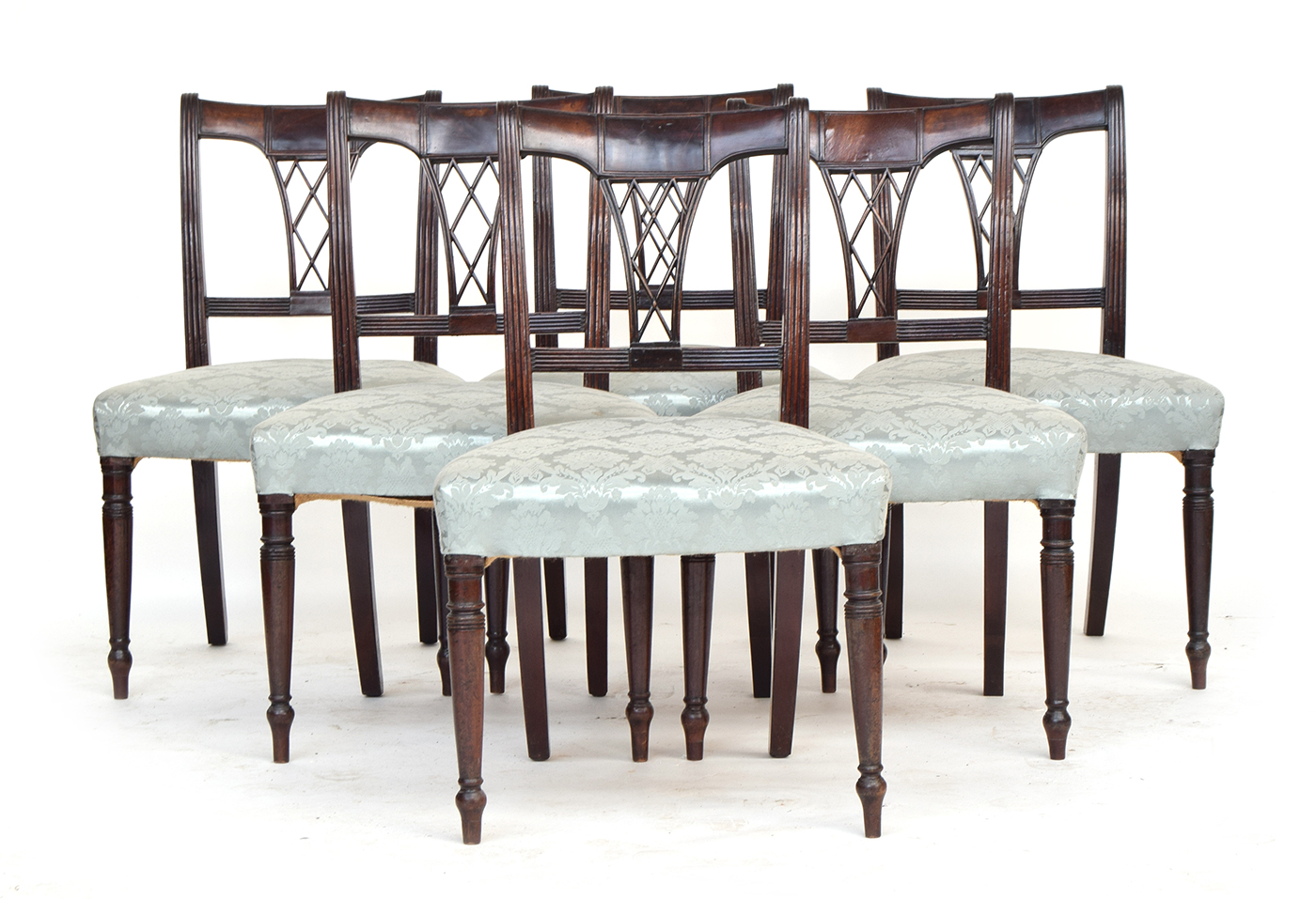A set of six Regency dining chairs, with lattice backs above stuffover seats, on turned legs