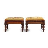 A pair of early 20th century embroidered footstools raised on turned legs, each 29cm square