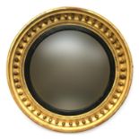 A Regency giltwood convex circular mirror wall mirror, the original plate within an ebonised