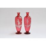 A pair of Mary Gregory style cranberry glass baluster vases, hand painted with white enamel, one