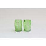 A pair of Mary Gregory style green glass tumblers, each decorated with white enamel depicting a