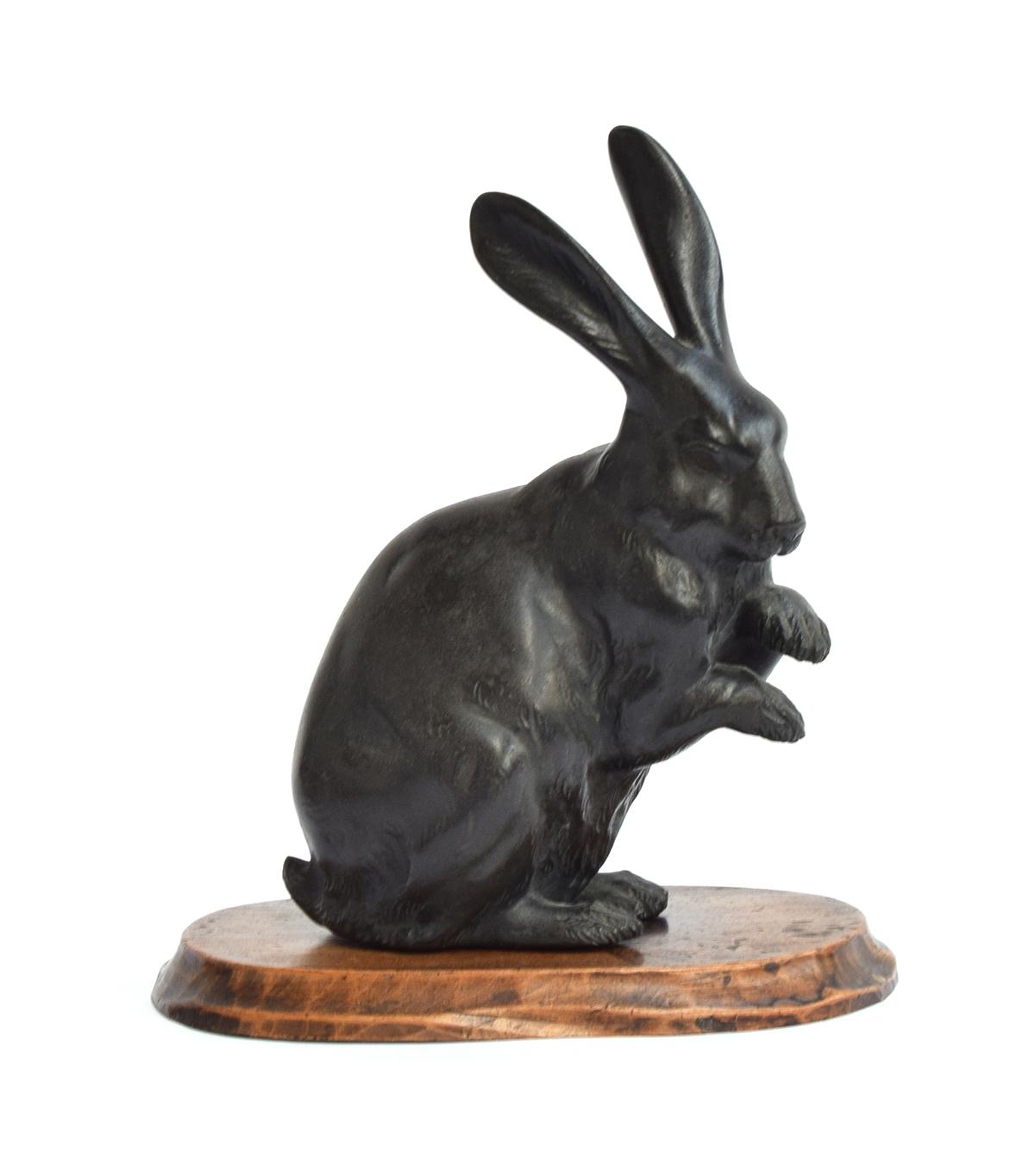 A Japanese bronze figure of a hare, with impressed seal mark to base (Norimitsu?), on hardwood