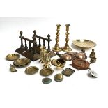 A mixed lot of brass items to include a pair of candlesticks; fire dogs; ashtrays; spill vases etc