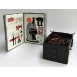 A Tasco 1200X microscope set; together with a vintage volt meter in case
