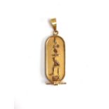 An Egyptian gold coloured metal 'ingot' pendant, cast with hieroglyphics