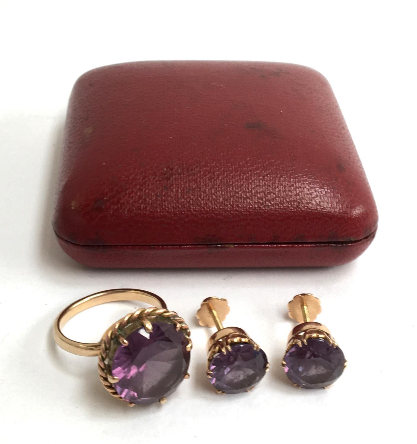 A yellow metal ring and earrings in red box set with a purple cut glass