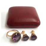 A yellow metal ring and earrings in red box set with a purple cut glass