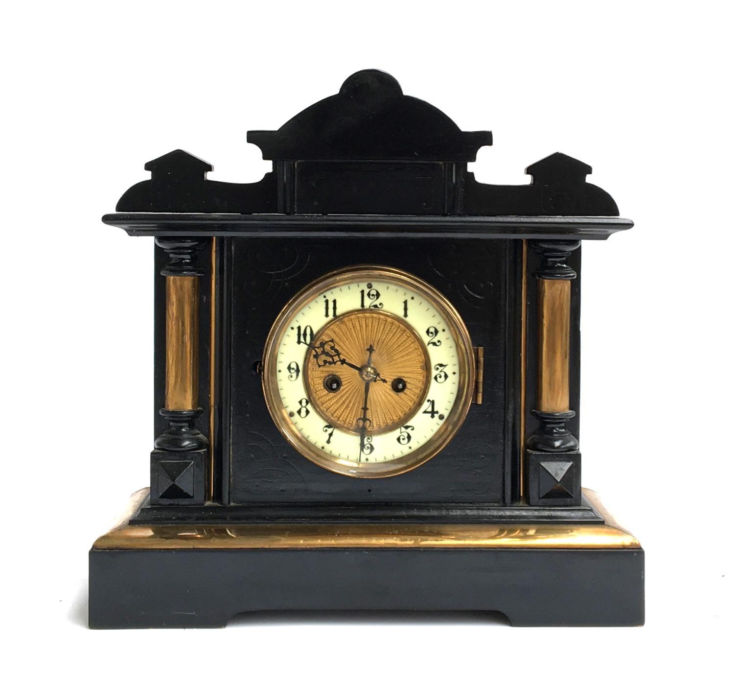 An ebonised mantel clock, dial with Arabic numerals, flanked by columns on either side