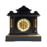 An ebonised mantel clock, dial with Arabic numerals, flanked by columns on either side