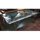 A glass topped coffee table on wrought iron scrolling base, parcel gilt decoration with hoof feet,