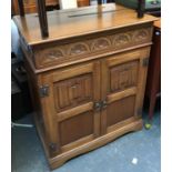 A carved oak cupboard with linen fold carving, hinged lid with two cupboard doors, 74cmW