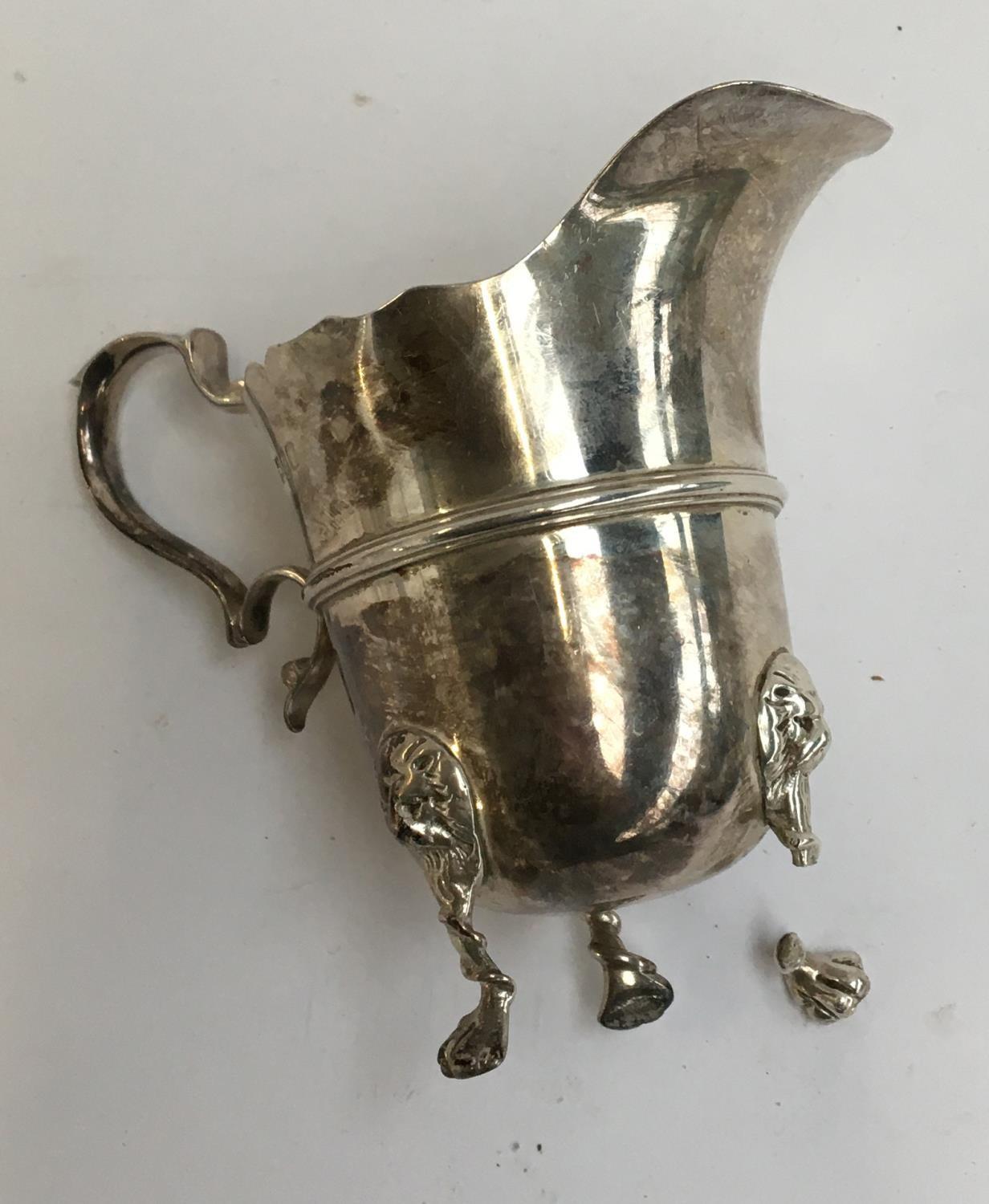 An early 20th century silver milk jug, three feet with lion mask knees (af), 4.1oz