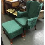 A green upholstered wingback armchair and footstool on cabriole legs