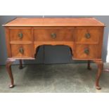 A walnut dressing table, kneehole with single drawer, flanked by four further drawers, on shell