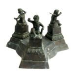 A cast metal triform urn stand with three figures