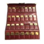A set of brass dominoes within fitted leather wallet (one missing)