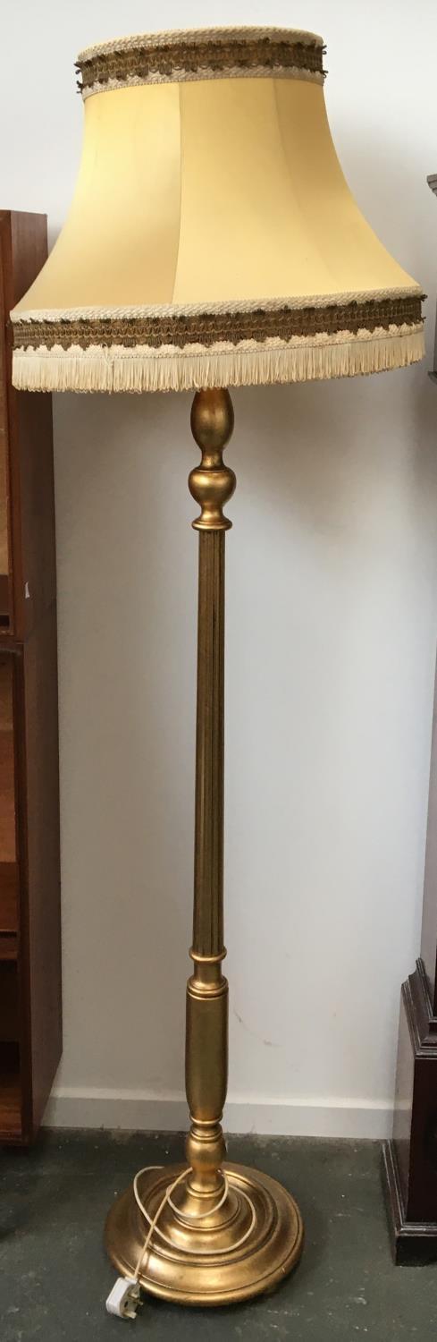 A gilt standard lamp with shade