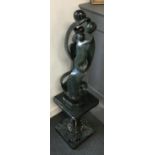 A serpentine marble abstract sculpture of figures embracing, on plinth, 107cmH