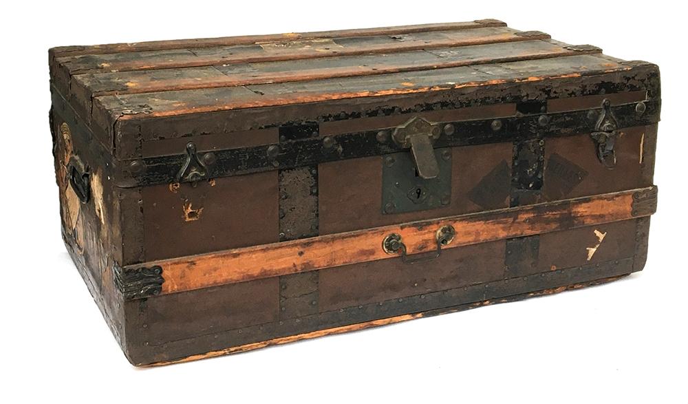 A wood banded travel trunk with metal brackets, with various travel labels, including Jerusalem,