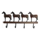 A mid 20th century coat rack, of four hooks with four horses above, in blankets, 39cmW